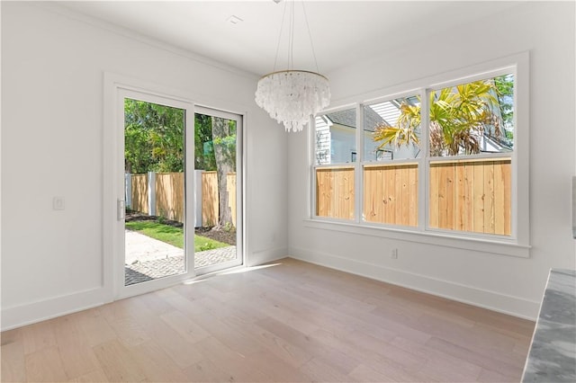 unfurnished dining area featuring light wood-style floors, baseboards, and an inviting chandelier