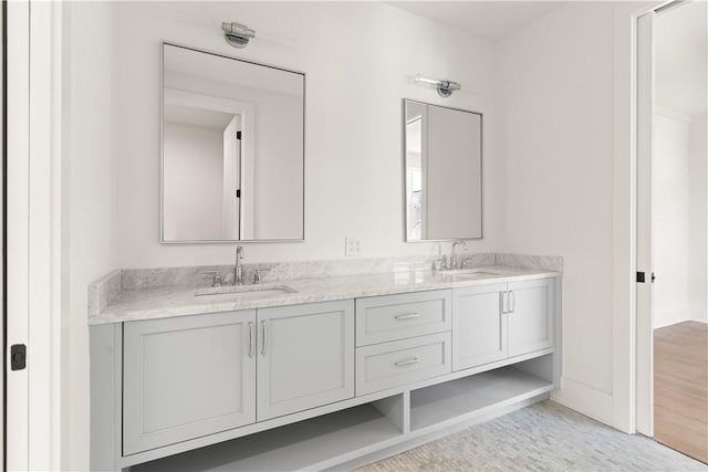 full bathroom with double vanity, a sink, and baseboards