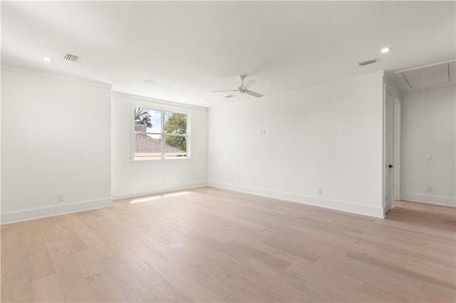 unfurnished room with baseboards, attic access, light wood finished floors, and visible vents