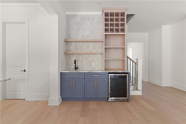bar with light wood-style floors, wet bar, wine cooler, and baseboards