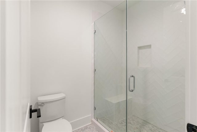bathroom featuring toilet, baseboards, and a shower stall
