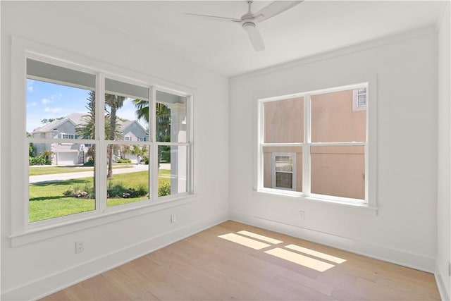 empty room featuring baseboards, a ceiling fan, and wood finished floors