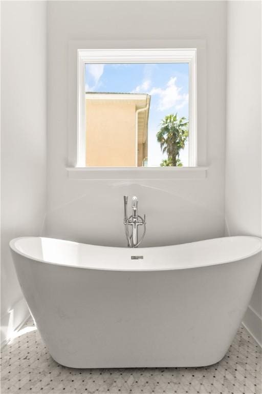 bathroom with baseboards, a freestanding bath, and tile patterned floors