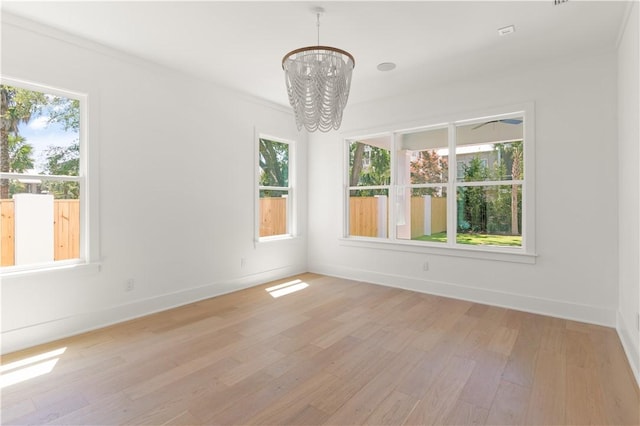 spare room with light wood-type flooring, baseboards, and an inviting chandelier