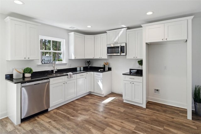 kitchen with white cabinets, appliances with stainless steel finishes, dark wood-type flooring, and sink