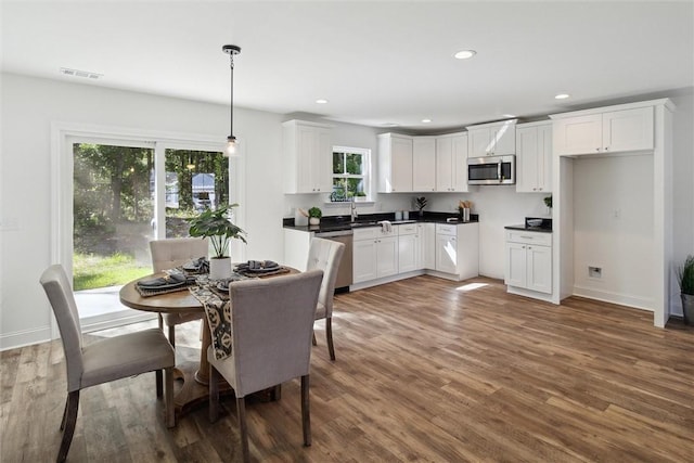 kitchen with sink, dark hardwood / wood-style floors, pendant lighting, white cabinets, and appliances with stainless steel finishes