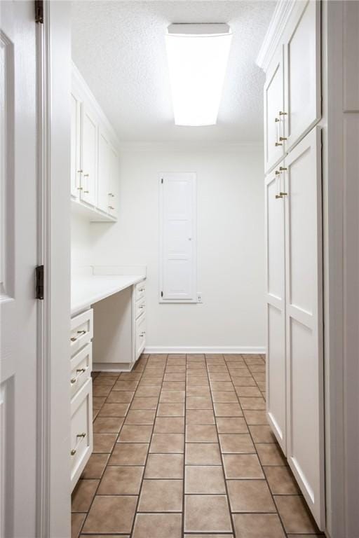 kitchen featuring light tile patterned flooring, white cabinetry, built in desk, and a textured ceiling