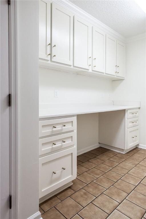 unfurnished office featuring ornamental molding, light tile patterned floors, and a textured ceiling