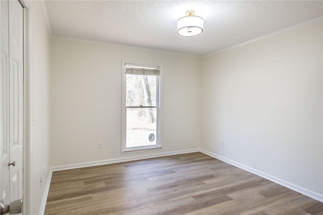 spare room featuring light wood-type flooring, crown molding, and a textured ceiling