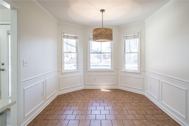 unfurnished dining area featuring dark tile patterned floors, crown molding, and plenty of natural light