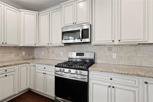 105 Gascoigne Ave Unit 204, Saint Simons Island, GA 31522 - kitchen featuring appliances with stainless steel finishes, decorative backsplash, white cabinets, and light stone countertops