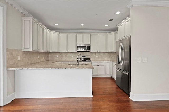 105 Gascoigne Ave Unit 204, Saint Simons Island, GA 31522 - kitchen with appliances with stainless steel finishes, a peninsula, light stone counters, tasteful backsplash, and recessed lighting