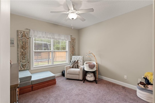 living area with ceiling fan, carpet floors, and a textured ceiling