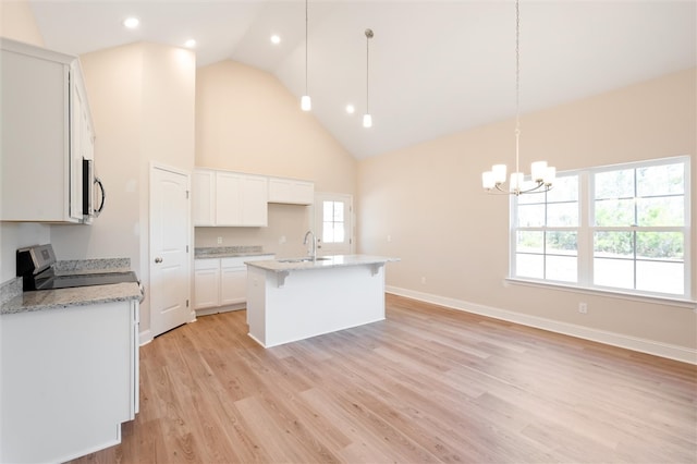 kitchen featuring high vaulted ceiling, a sink, white cabinetry, light wood-style floors, and an island with sink