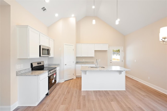 kitchen featuring a sink, white cabinetry, appliances with stainless steel finishes, light wood-type flooring, and a center island with sink