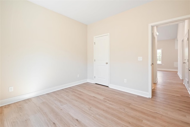 spare room featuring attic access, light wood-style flooring, and baseboards