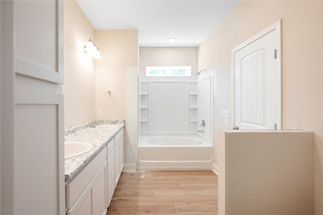 bathroom featuring double vanity, a sink, washtub / shower combination, and wood finished floors