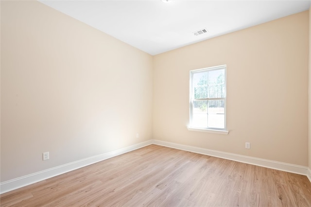 unfurnished room featuring light wood-type flooring, visible vents, and baseboards