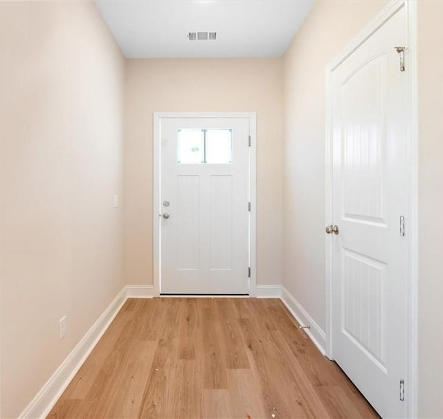 doorway to outside with light wood-style flooring, visible vents, and baseboards