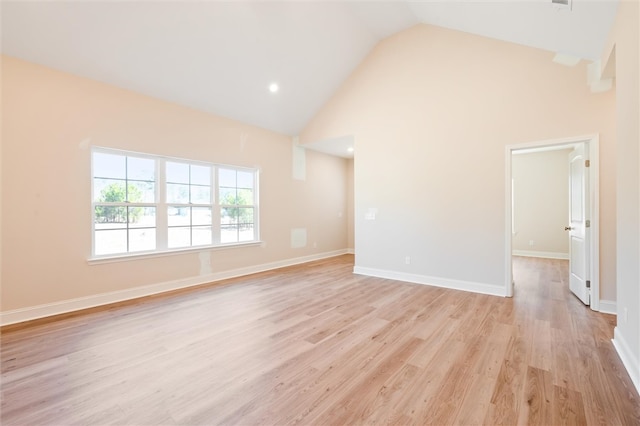 empty room with high vaulted ceiling, baseboards, and light wood finished floors