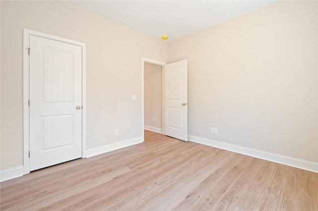 spare room featuring baseboards and light wood-style floors