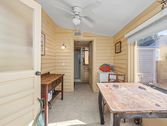 interior space featuring vaulted ceiling, ceiling fan, and wood walls