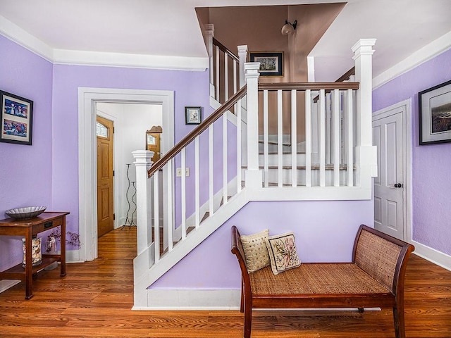 stairs with ornate columns and wood-type flooring