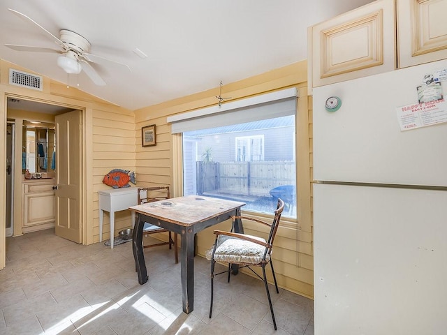 dining room with lofted ceiling, wooden walls, and ceiling fan