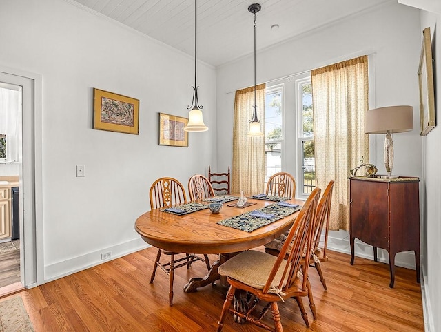 dining space with ornamental molding and light wood-type flooring