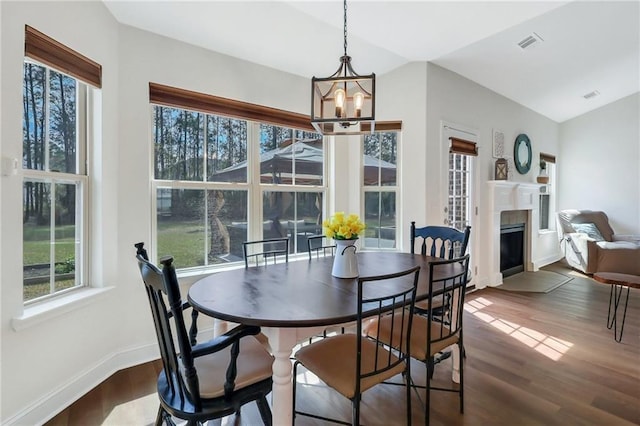 62 Wellington Cir, Brunswick, GA 31525 - dining space with a chandelier, dark wood-type flooring, baseboards, a fireplace, and lofted ceiling