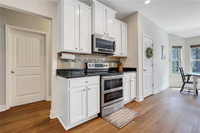 62 Wellington Cir, Brunswick, GA 31525 - kitchen with appliances with stainless steel finishes, light wood-style flooring, decorative backsplash, dark countertops, and white cabinetry