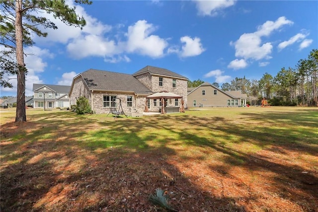 62 Wellington Cir, Brunswick, GA 31525 - back of property with stone siding, a playground, a gazebo, and a lawn