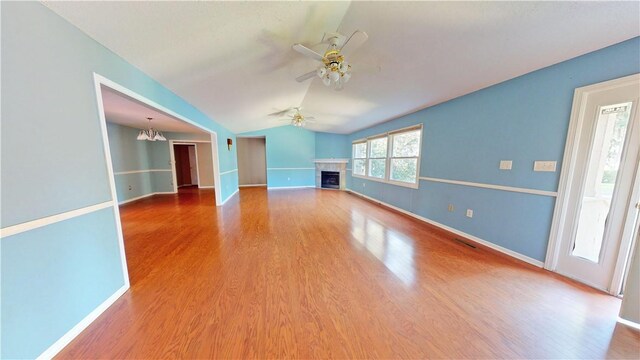 unfurnished living room featuring ceiling fan with notable chandelier, wood-type flooring, and lofted ceiling