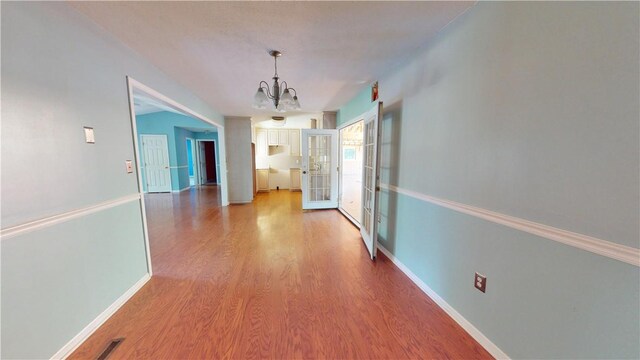 corridor featuring light hardwood / wood-style flooring and a notable chandelier