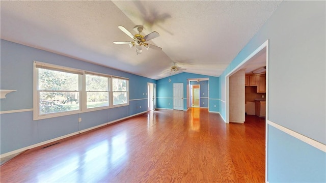 unfurnished room featuring hardwood / wood-style flooring, ceiling fan, a textured ceiling, and vaulted ceiling