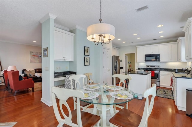 dining space with dark wood finished floors, visible vents, and ornamental molding