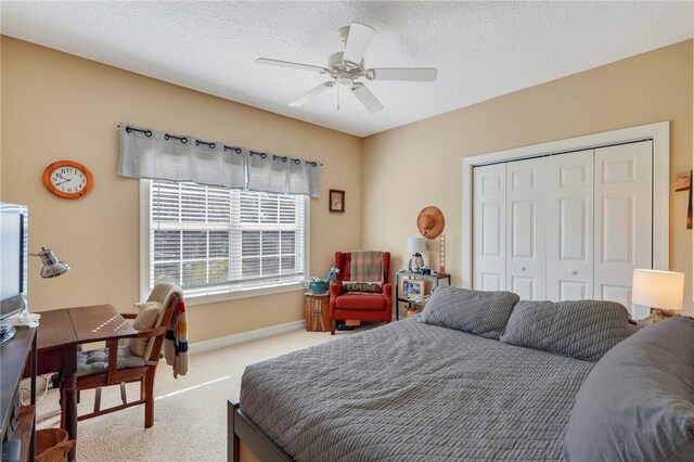 bedroom with a ceiling fan, a closet, baseboards, a textured ceiling, and carpet flooring