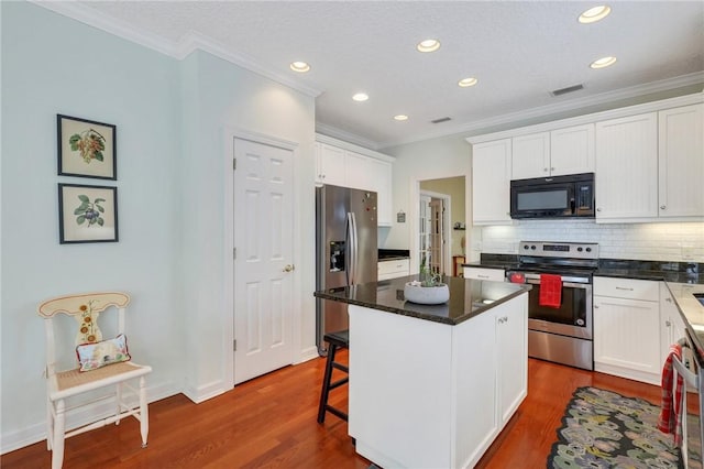 kitchen with visible vents, white cabinetry, appliances with stainless steel finishes, and crown molding