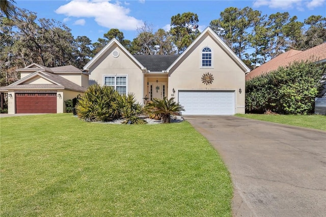 traditional-style house featuring a garage, driveway, a front lawn, and stucco siding