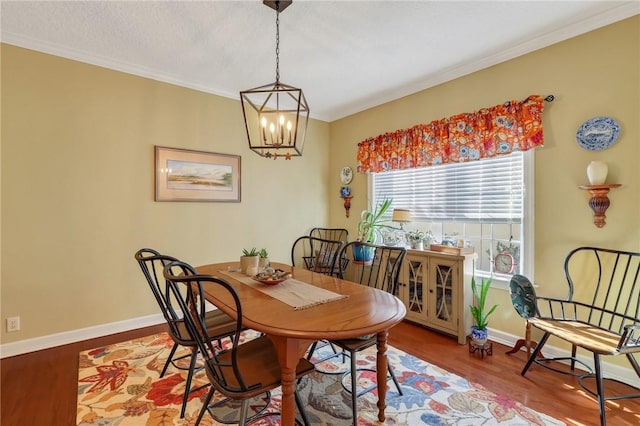 dining space with a chandelier, wood finished floors, crown molding, and baseboards
