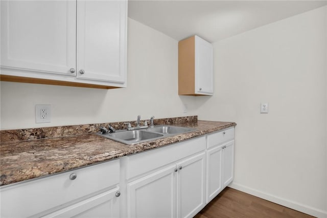 kitchen with white cabinets, dark hardwood / wood-style floors, dark stone counters, and sink