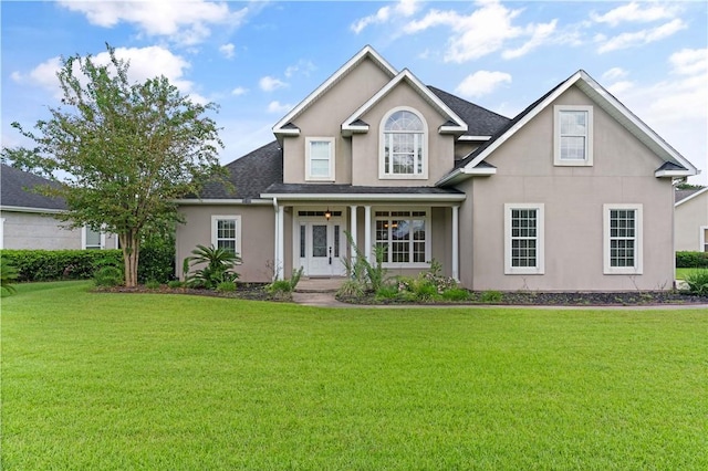 view of front of house with a porch, a shingled roof, a front yard, and stucco siding