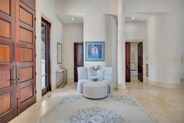 sitting room featuring ornate columns and a towering ceiling