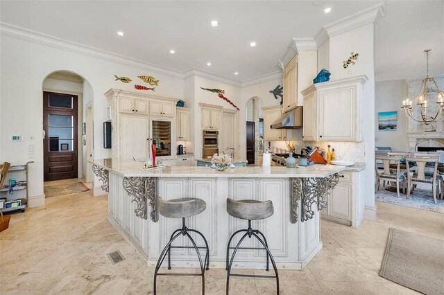 kitchen with cream cabinetry, a large island with sink, a kitchen breakfast bar, and pendant lighting