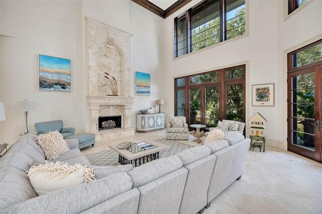 living room with a fireplace, a towering ceiling, and ornamental molding