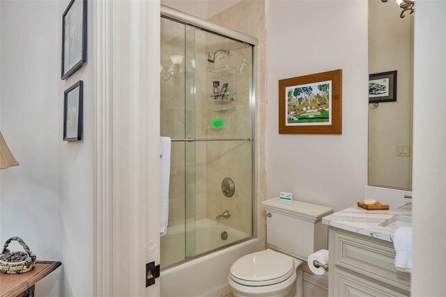 full bathroom featuring combined bath / shower with glass door, vanity, and toilet