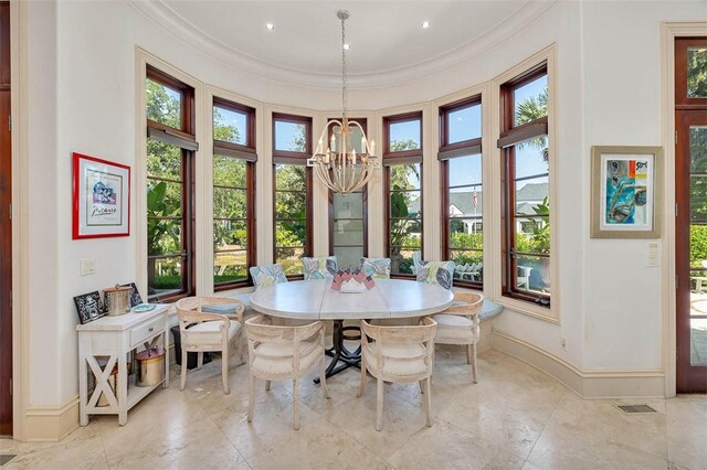 dining space featuring a towering ceiling, ornamental molding, and an inviting chandelier