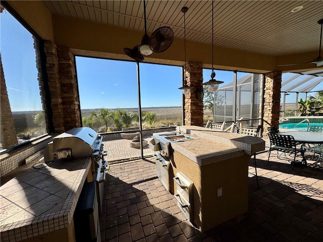 view of patio / terrace with an outdoor kitchen, ceiling fan, a lanai, and area for grilling