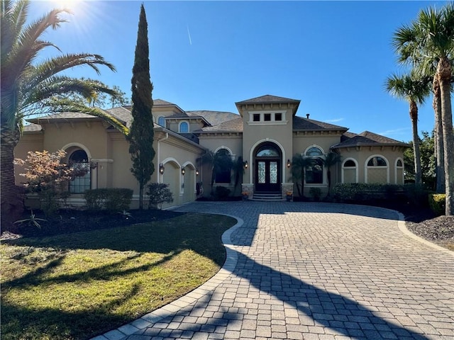 mediterranean / spanish house featuring a front lawn and french doors