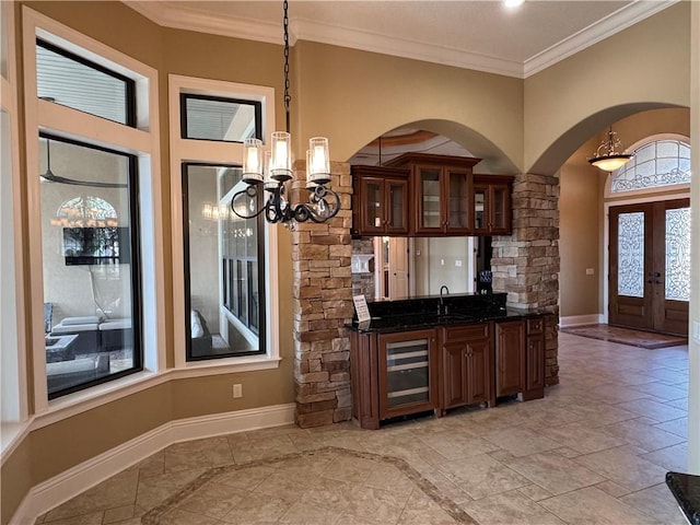 kitchen with french doors, sink, crown molding, a chandelier, and decorative light fixtures